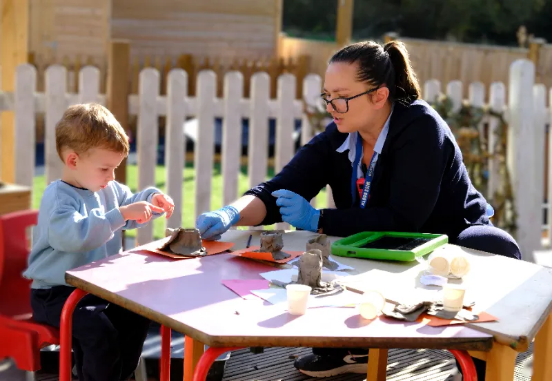 adult and child sat at a table outside doing an activity